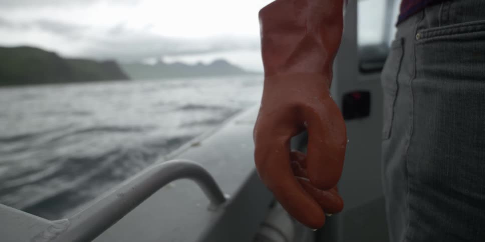 Man rides on a boat while wearing gloves