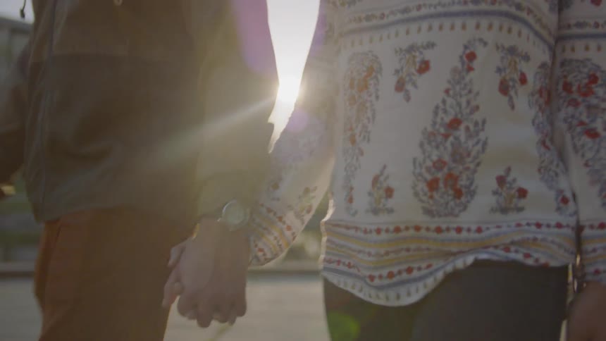 Two people walk outside holding hands