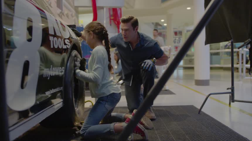 A girl loosens then tightens lug nuts on a race car