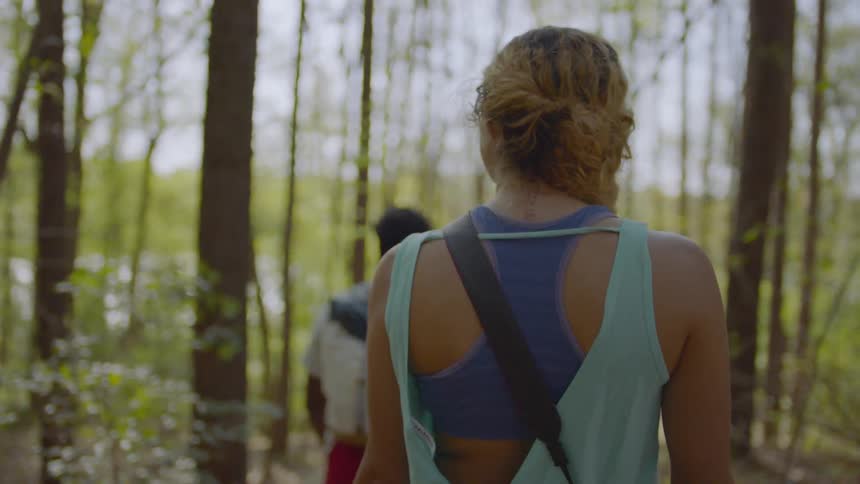 A man and woman are hiking through the forest together