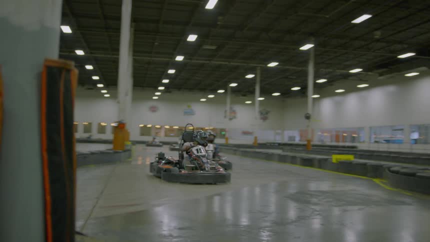 People ride go-karts on an indoor track