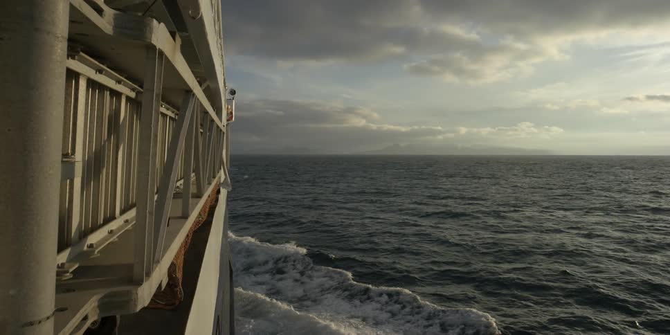 A ship is moving through the ocean on a cloudy day