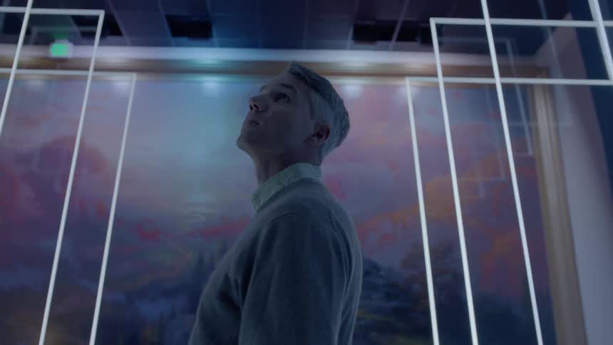 A man is walking through a museum of art and stops to admire a piece