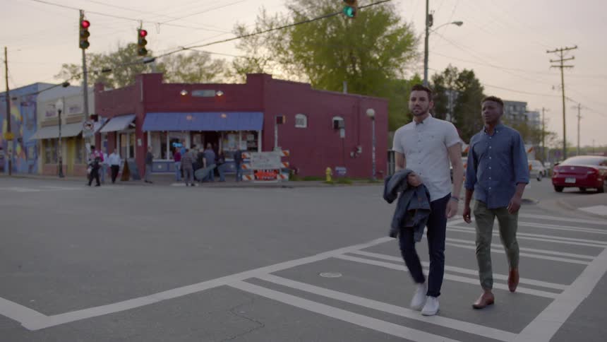 Two men crossing a city street in a crosswalk area
