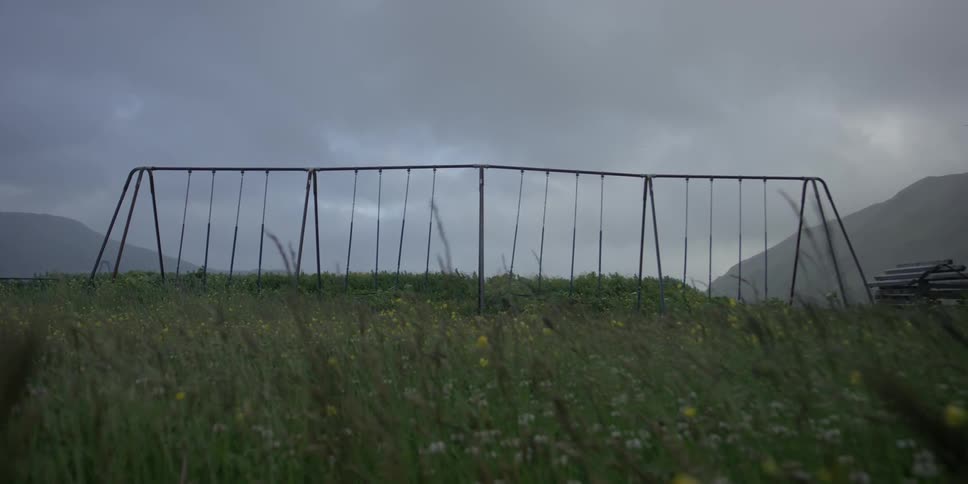 Wind blows grass near swing set