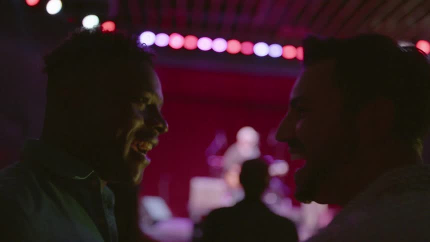 Two men talk in a club