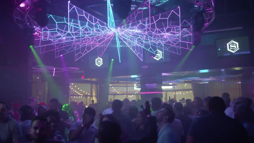 Crowd dancing in a club while lights flash all around above them