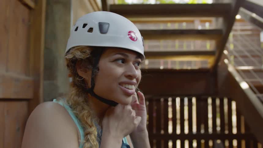 A woman smiles and fastens a helmet