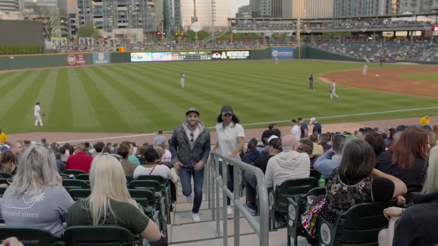 A man and woman are running up the stands at a baseball game