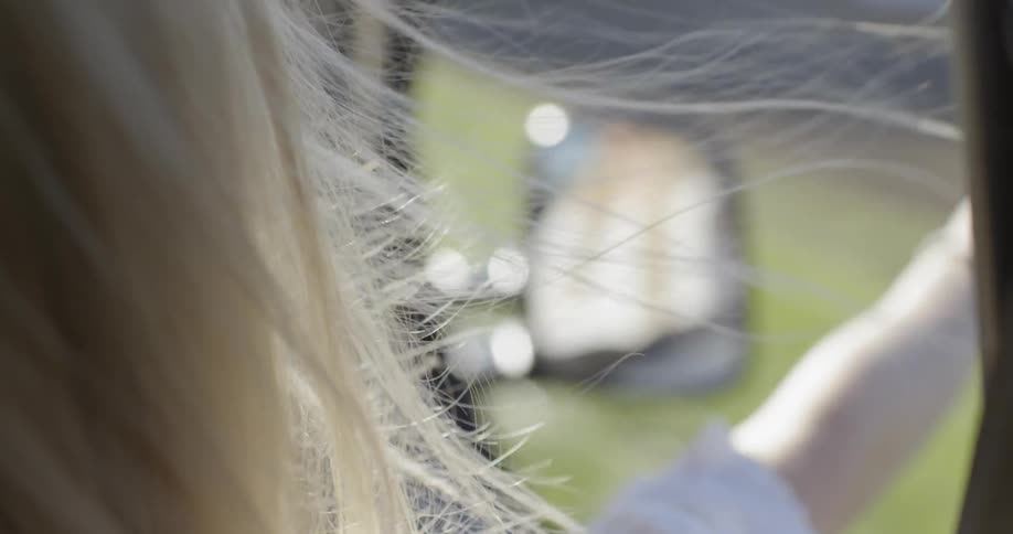 Blond holding her arm out the window of a moving vehicle on a sunny day