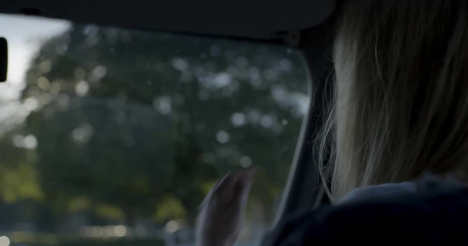 A woman sits in the passenger seat of a moving car