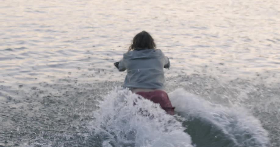 Man runs and dives into a lake at sunset