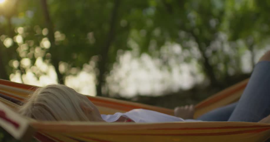 A woman lays in a swinging hammock