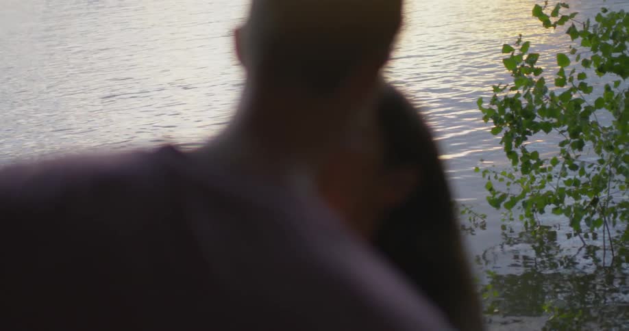 Man and woman kiss outside by a lake