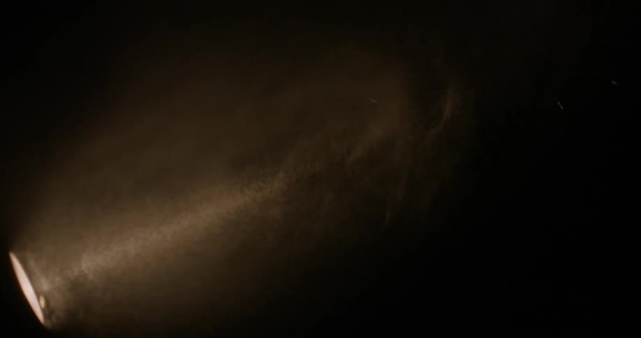 Rain is falling in front of a flashlight