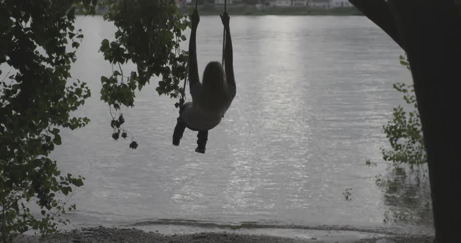 A woman swings on a rope swing near a lake