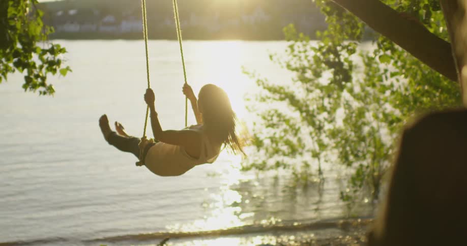 A woman swings by the lake
