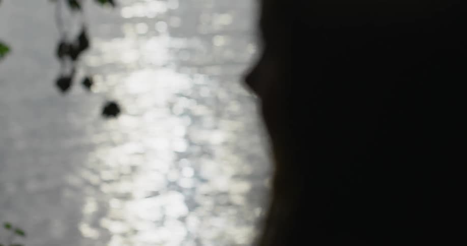 A woman stands next to a rippling lake