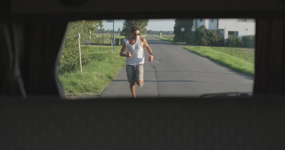 A man jogs behind a moving vehicle