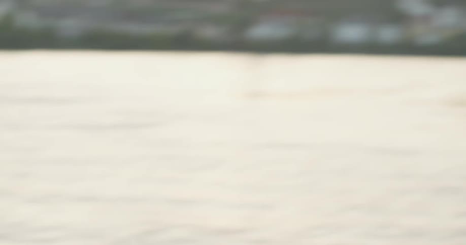 Two men play catch with a soccer ball next to a lake