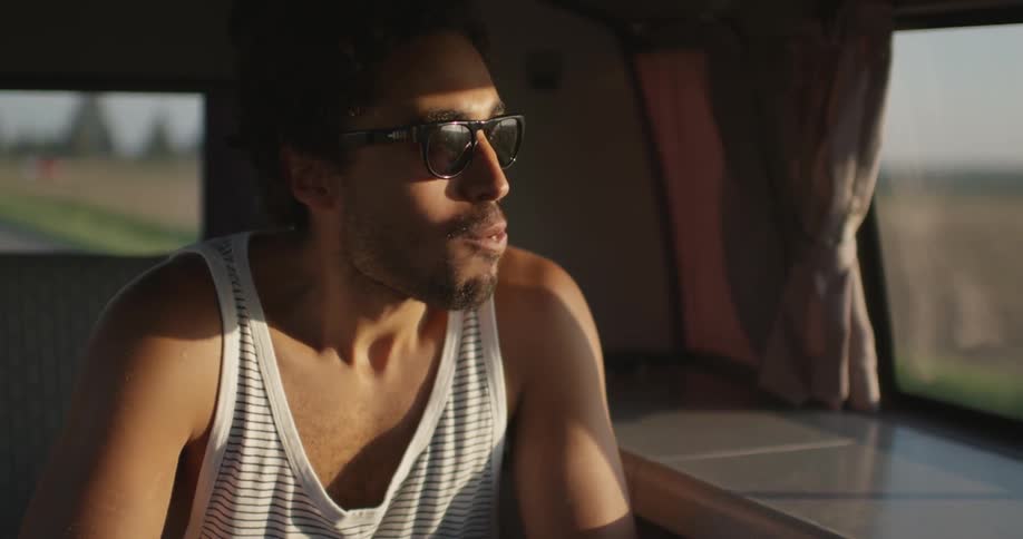 Man eating an apple as he looks out the window of a moving vehicle