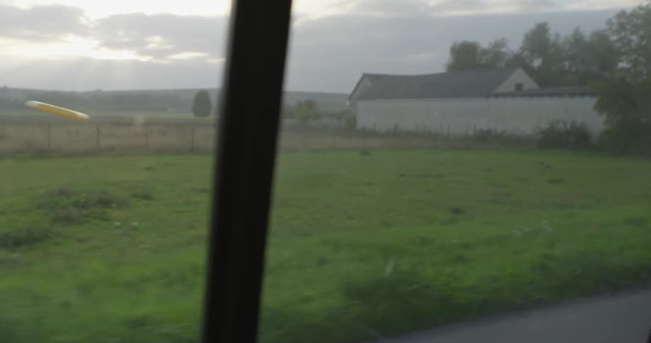 Two guys are playing frisbee on the side of the road as a van passes