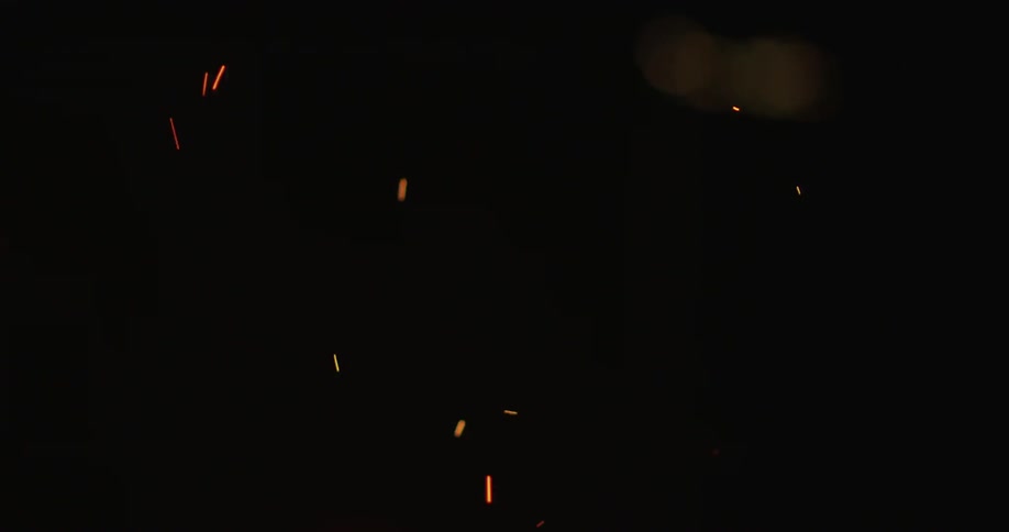 Embers rise from a campfire at night