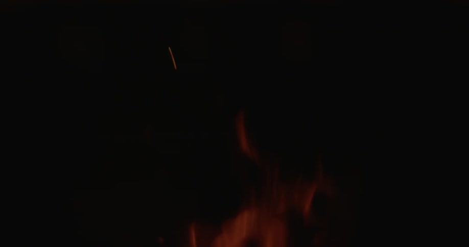 Man sits next to a campfire at night