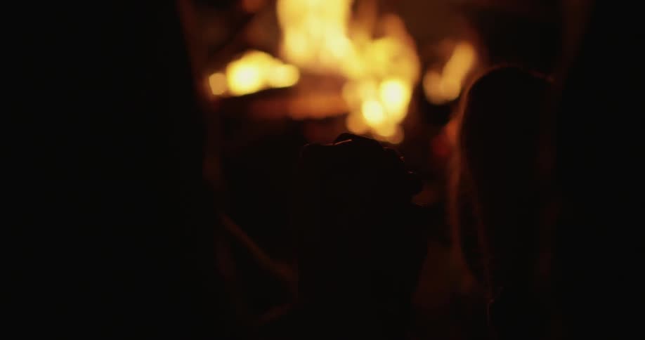 People sit next to a campfire at night