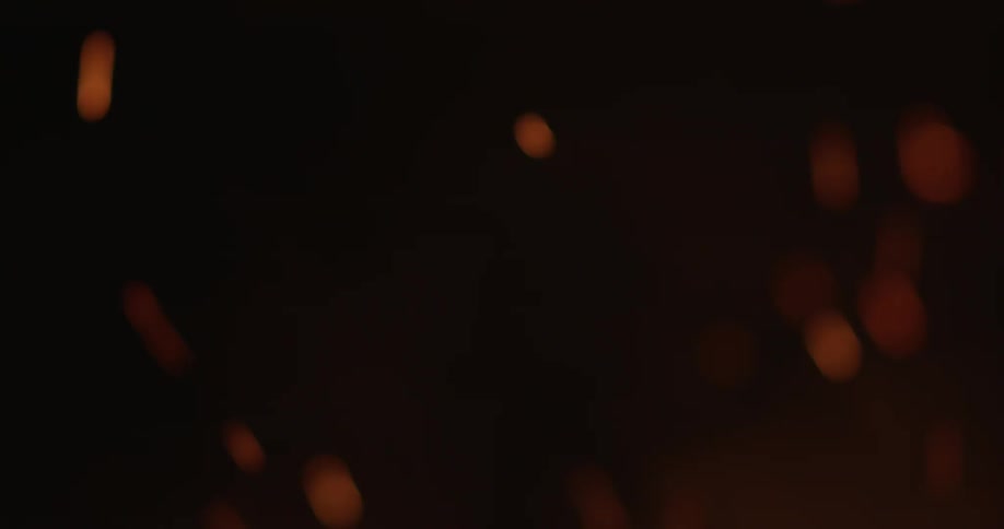 A campfire is stoked with a large stick