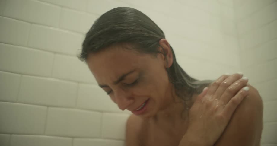 A woman is sitting in a shower crying