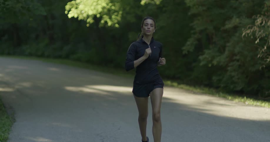 Woman jogs through a forested area