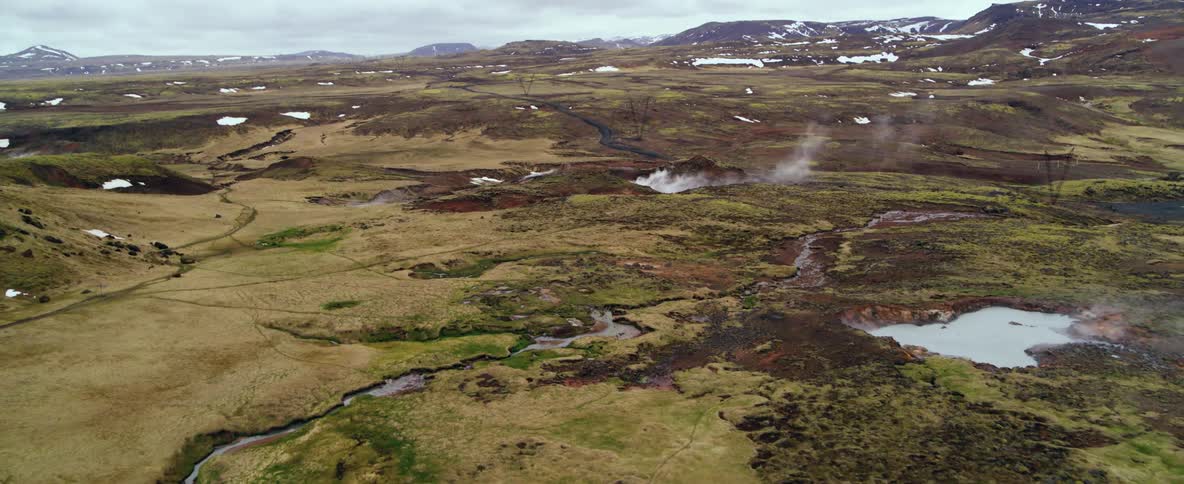 Steam is rising from hot springs in a natural landscape on a cold day
