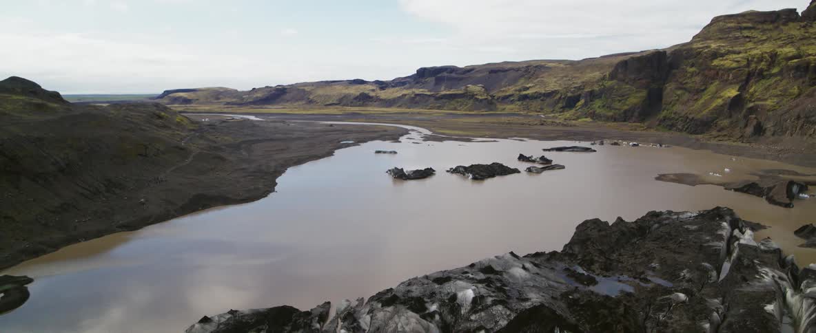 Muddy snow sits by a mountain lake