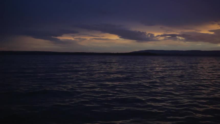 The ocean tide rolls under a cloudy dusk sky