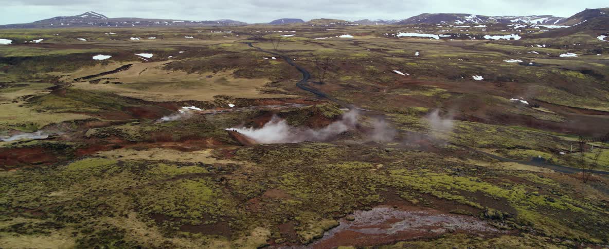 Steam is rising from hot springs in a natural landscape on a cold day