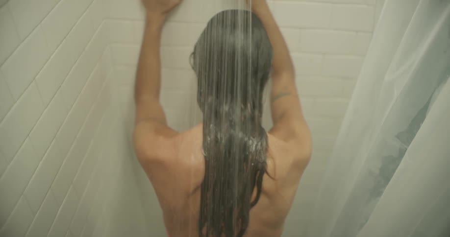 A woman leans against the wall while showering
