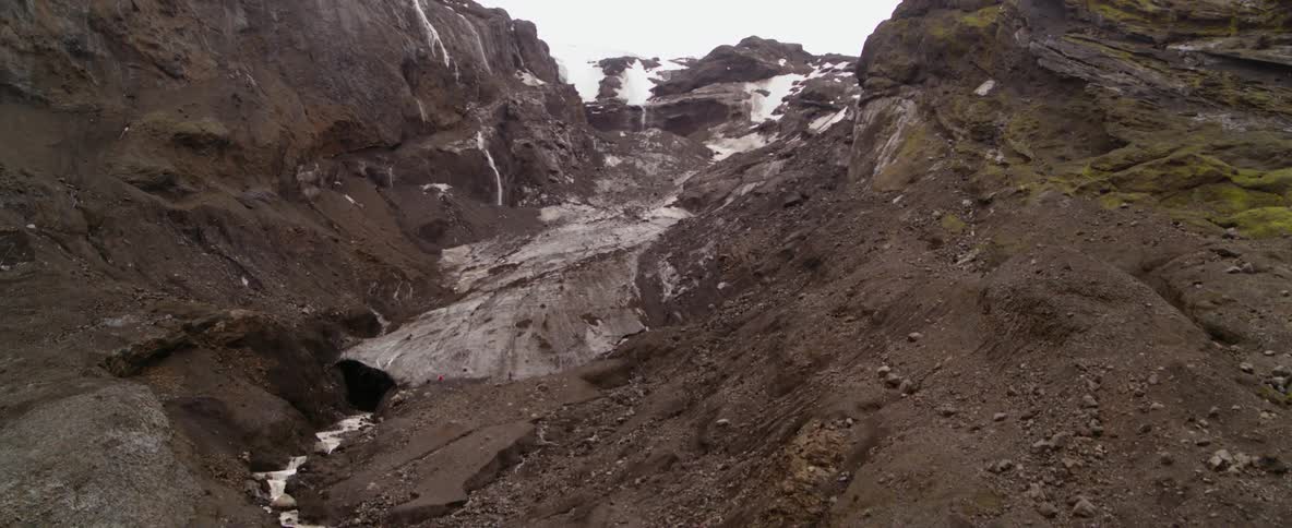 Man stands near a helicopter at the base of a mountain