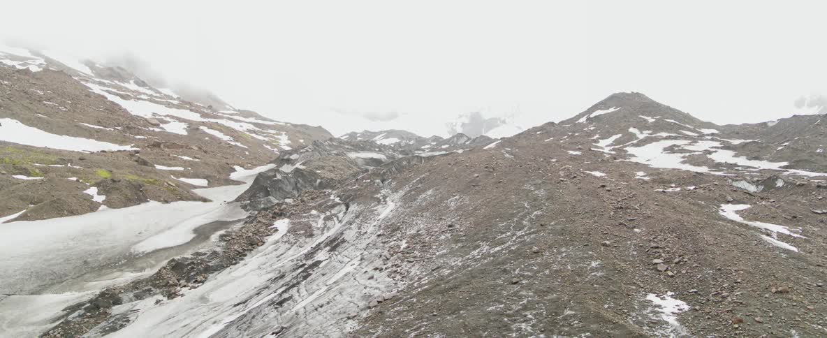 Helicopter sitting high on a mountain ridge in a snowy area