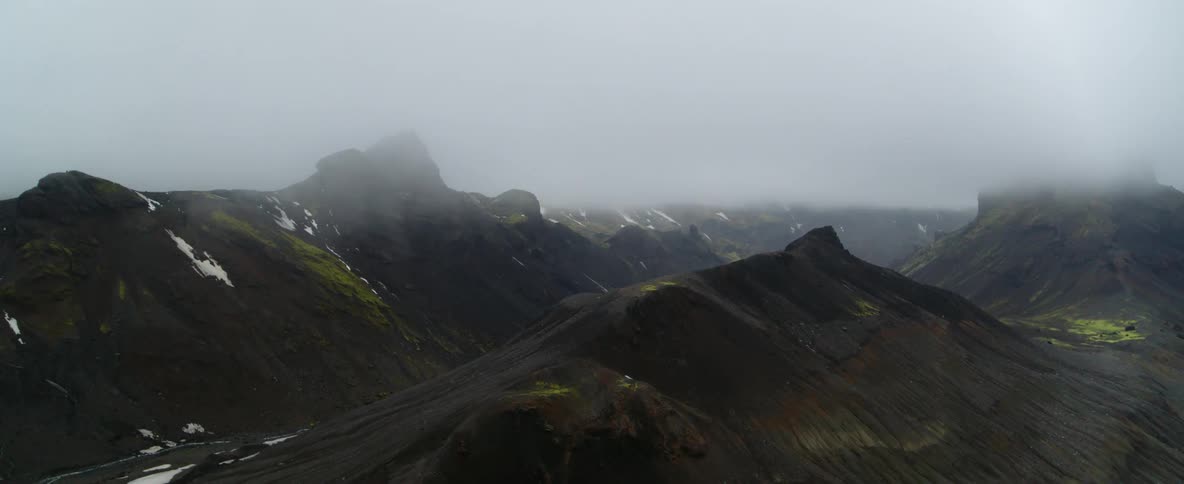 Fog hangs above the dark brown mountains