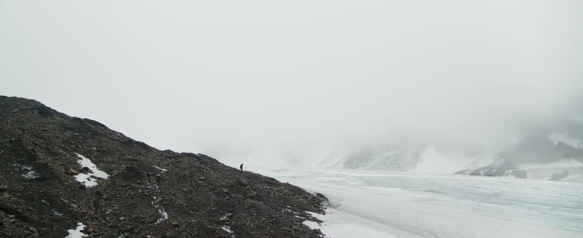 A man stands on rocks by frozen water