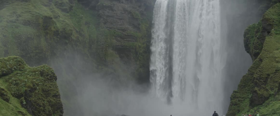 People look at a huge cascading waterfall