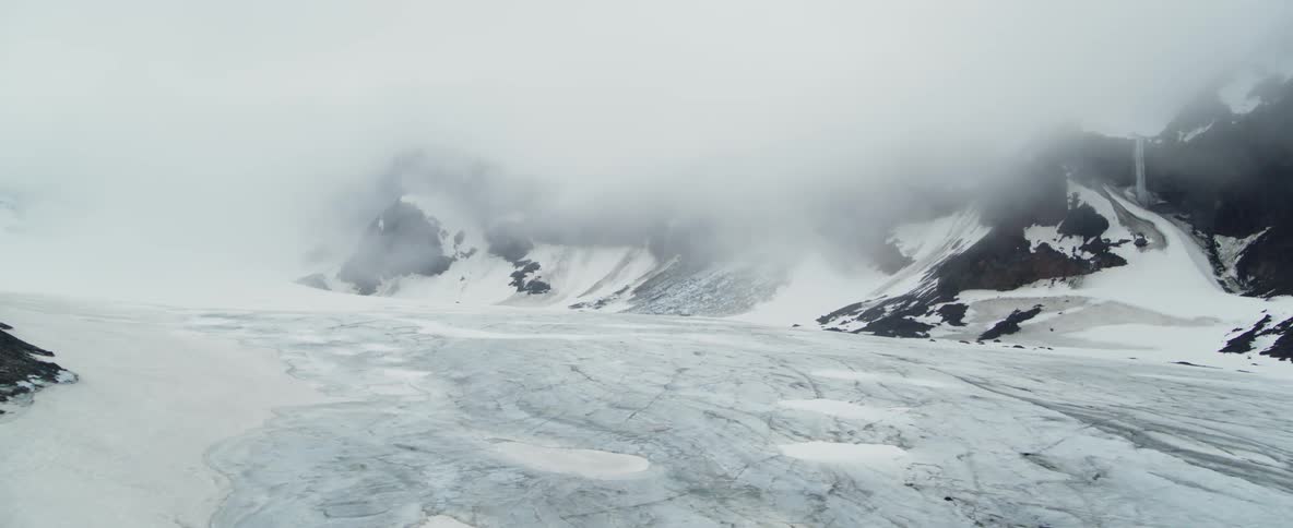 Clouds hang over snow and ice covered rocks