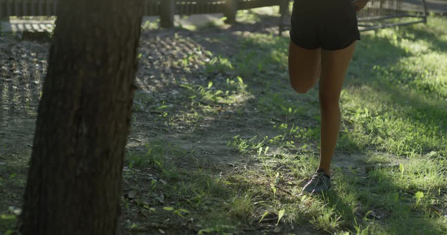 A woman is doing leg stretches in a park in the morning
