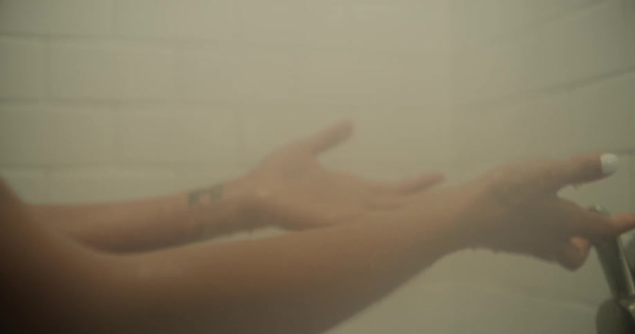 Woman holds her hands under shower water