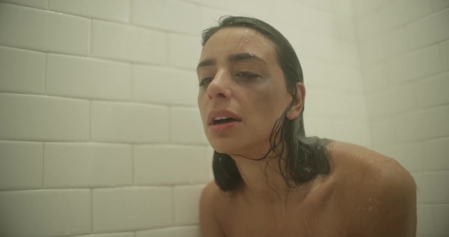 A woman with a black eye cries while showering