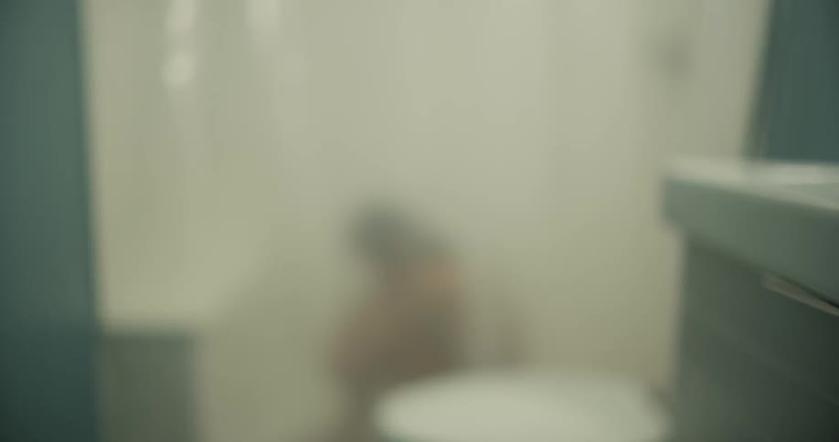 A woman sits and rocks in a shower