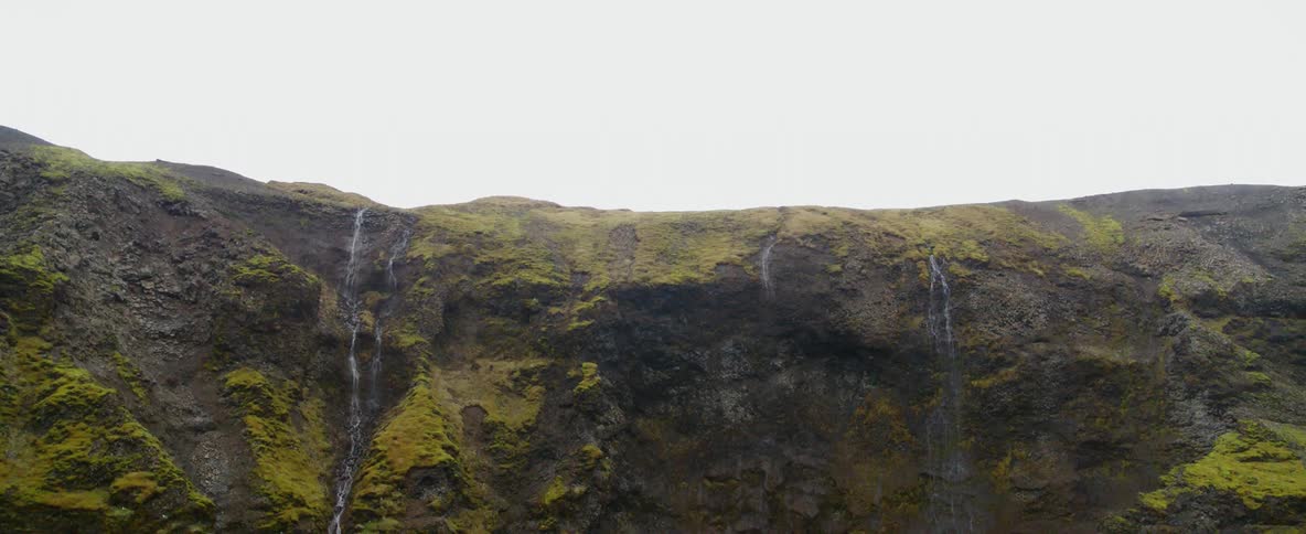 Waterfalls flow over a mossy cliffside