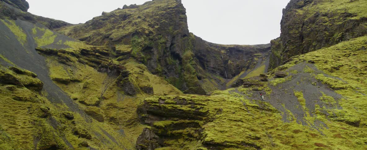 Two people are hiking up a mountain ridge on a cloudy day