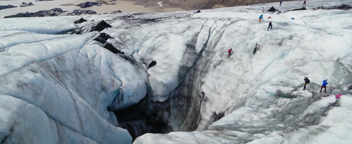 A group of climbers is navigating a cave in a glacier during the day